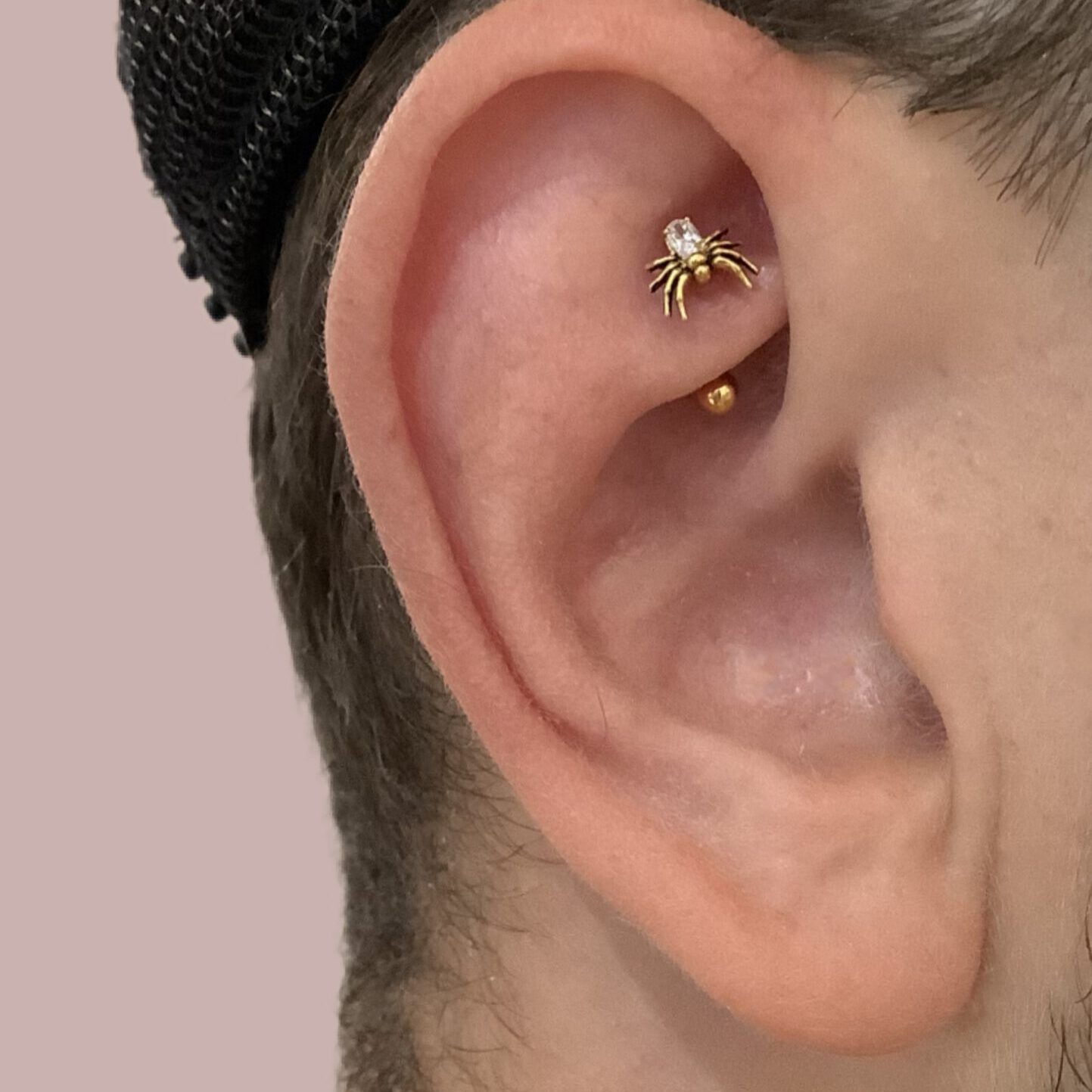 Süße goldene Spinne in Rookpiercing bei Fine Line Berlin. Diese gruselig süße Spinne wurde im Studio Fine Line Berlin von unserer Piercerin Miri (sie/ ihr) in einem Rook platziert.