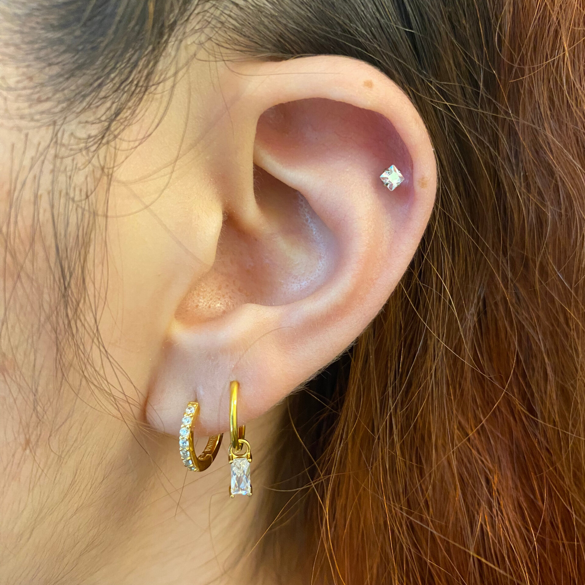Schmuckstyling von Miri. Einsetzen von goldenem/ kristallenem Piercingschmuck in Helix, Lobe und Upper Lobe. Dieser schöne goldene und Kristallene Schmuck wurde beim Schmuckstyling in ein Helix-, einen Upper Lobe- und Lobe- Piercing eingesetzt.