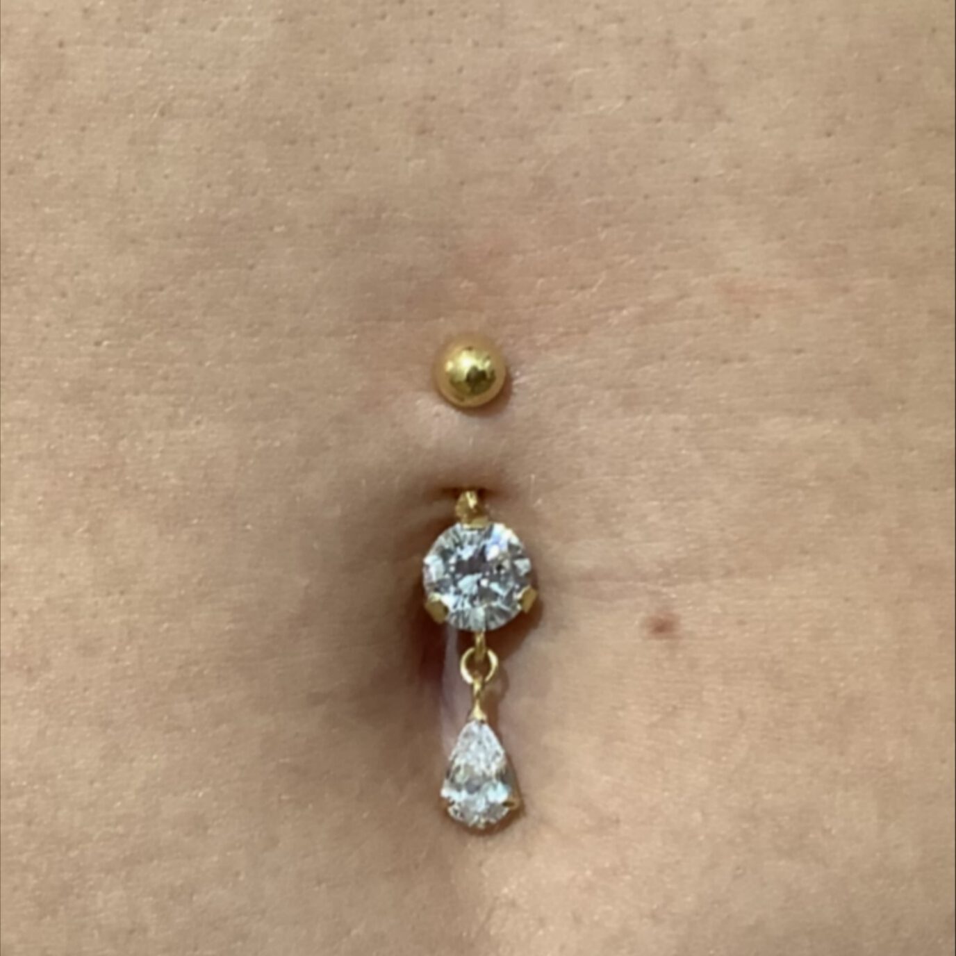 Bauchnabelpiercing in Gold mit großem Kristall und tropfenförmigem Kristallanhänger.